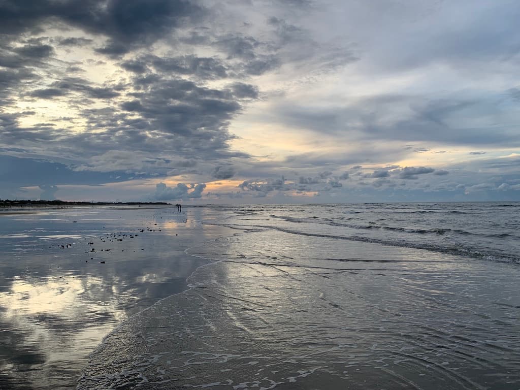 Poelen met kristalhelder water bij eb in Guajiru, met de weerspiegeling van de hemel op het natte zand.